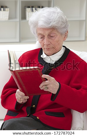 grey haired senior woman  relaxing at home reading a book