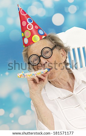 happy mature woman with funny big eye-glasses , party hat and noise maker
