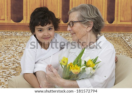 Little boy giving flowers to his grand mother