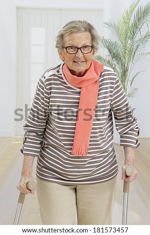 Smiling senior woman walking with crutches.