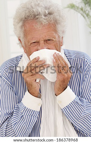 Senior man with white hair  having a cold , sneezing