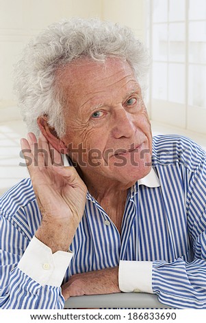 portrait of  senior man,  hard of hearing, placing hand on ear asking someone to speak up.
