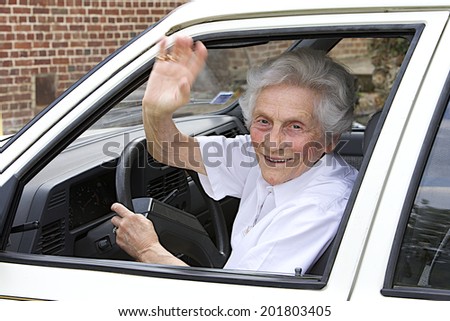 Portrait of a smiling aging woman sitting in a vehicle  saying goodbye with her hand