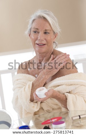 senior Woman applying moisturizer cream on her body