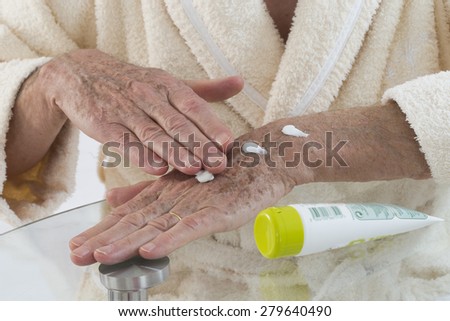 Old man applying hand cream at home