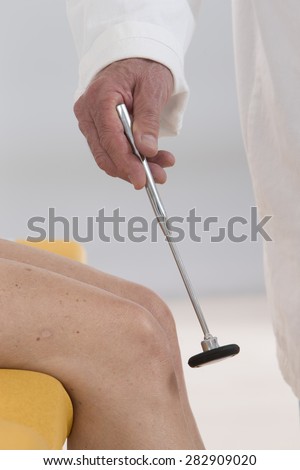 neurologist testing knee reflex on a female patient with  a hammer
