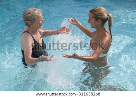 Disabled senior woman with therapist for aqua-gym reeducation