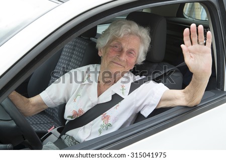 Smiling old woman sitting inside the car