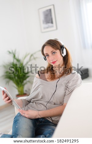 cheerful young women at home listening to music on her computer tablet