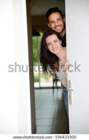 happy young couple welcome in their new house showing the door house keys