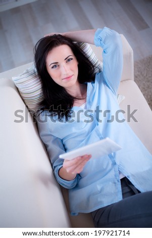 cheerful young brunette lying on her sofa relaxed at home