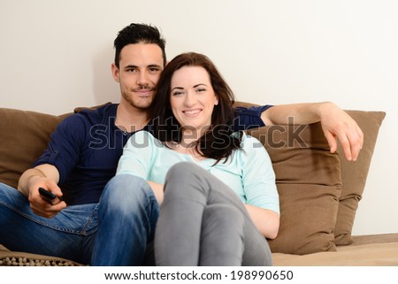 portrait of happy beautiful young couple relaxing on sofa together at home