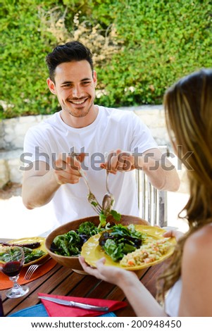 happy young man woman couple having lunch barbecue outdoor in summer with friends