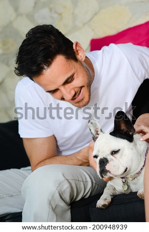 handsome young man with his dog pet french bulldog sitting outdoor in sofa