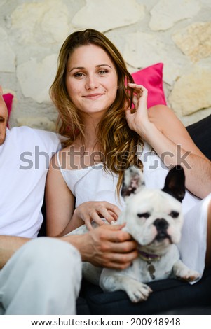 cheerful young woman with pet french bulldog in sofa outdoor
