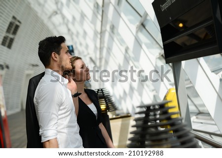 young business travelers man and woman in public transportation station looking for information and schedule
