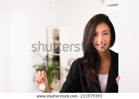 cheerful young businesswoman real estate agent holding and giving keys to a new rental house