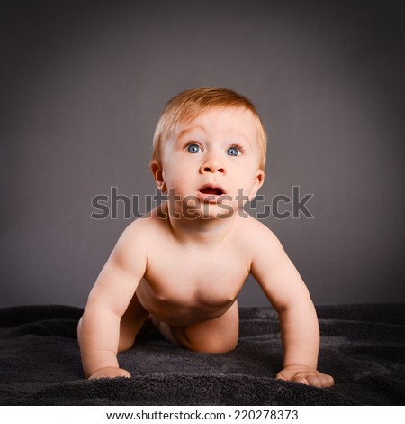 isolated studio portrait on grey background of lovely toddler baby boy playing and laughing