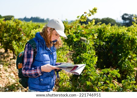 cheerful young woman hiking in the countryside searching her way and looking at map