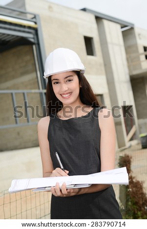 cheerful young woman architect supervising building construction site with a  blueprint