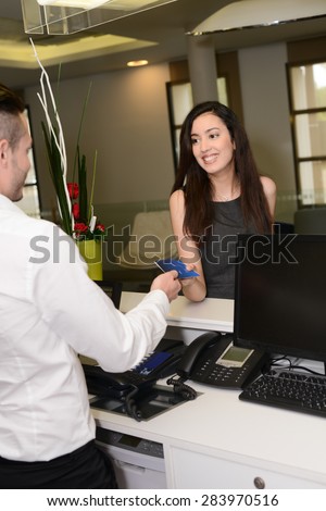 handsome young man receptionist handing over room keys to a beautiful woman in hotel front desk