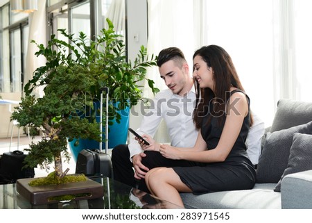 two business people man and woman playing with smartphone while waiting in airport lounge