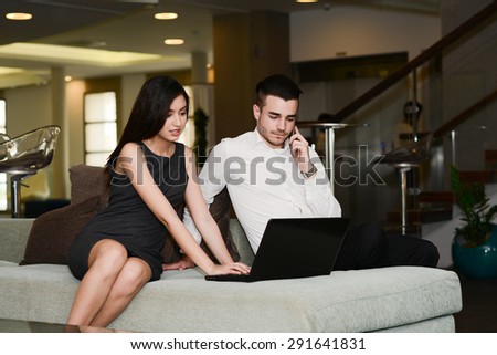 two business people man and woman working on a computer while waiting in airport lounge