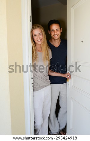 happy young couple man and woman opening door of their new home entrance