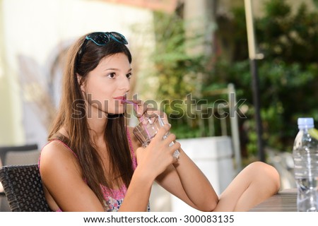 portrait of a beautiful young woman drinking a glass of water at a terrace outdoor