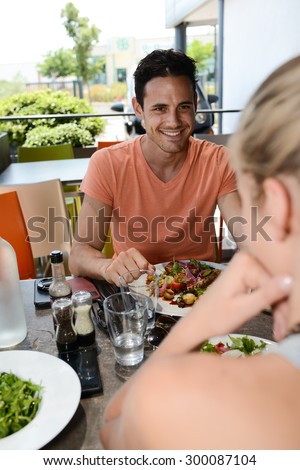 happy young couple on holiday having lunch in a restaurant terrace outdoor during summer