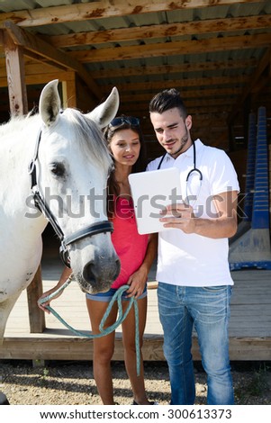 young man veterinary doing medical examination on beautiful white and gray camargue horse