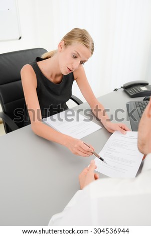 attractive young business woman with customer in office signing an agreement sales contract