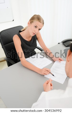 attractive young business woman with customer in office signing an agreement sales contract