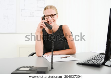 cheerful attractive young business woman wearing glasses in office having phone conversation