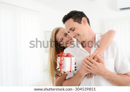 beautiful and cheerful young couple in love offering gift to each other for valentine day or birthday