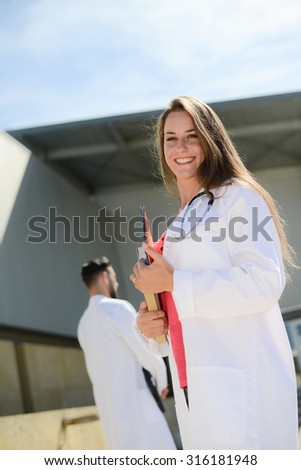 portrait of an attractive cheerful young medical student woman outdoor in front of hospital university campus