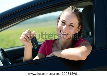 cheerful and happy young woman in car showing car keys