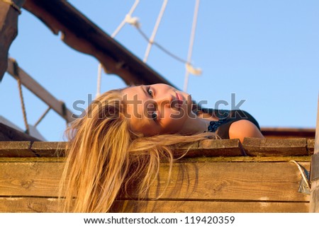 Pretty girl lying on the deck of an old wooden ship