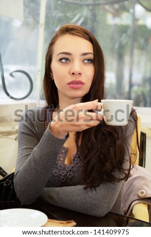Pretty thoughtful woman drinking in a cozy cafe