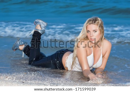 Sexy young woman in wet clothes posing on the beach