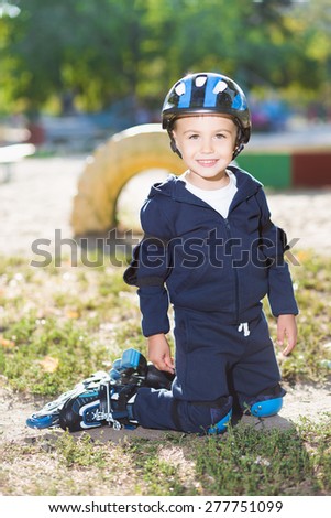 Smiling little skater boy posing on the knee pads