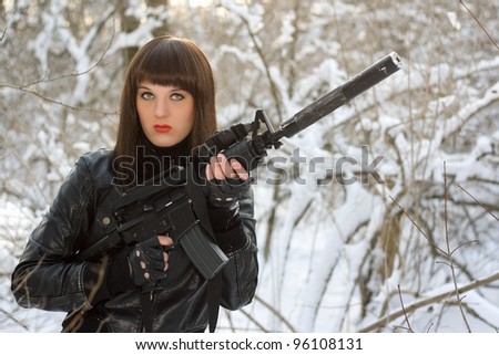 Portrait of young lady with a rifle in winter forest