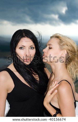 Portrait of the two young women against the cloudy sky