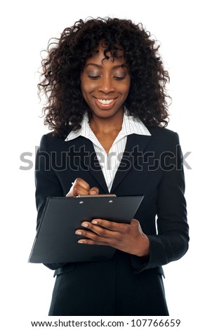 African female executive writing on notepad looking down and smiling