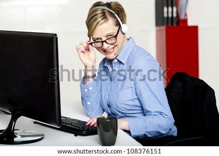 Female call center executive looking at you from behind her eyeglasses and smiling
