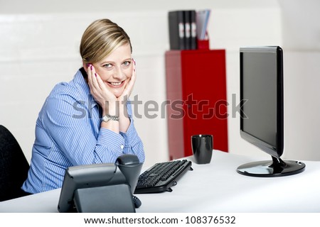 Charming corporate lady posing in office. Sitting with hands on her cheek