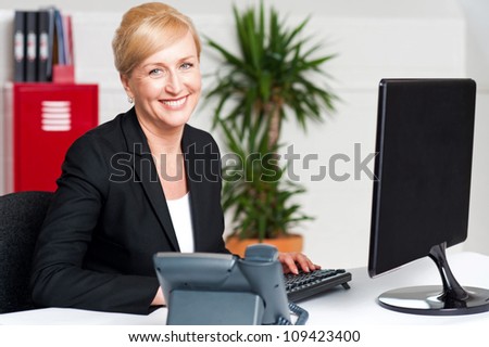 Smiling corporate woman typing on keyboard, working in office