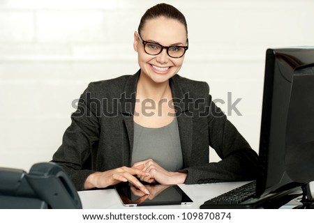 Pretty manager working on wireless tablet device sitting in her office