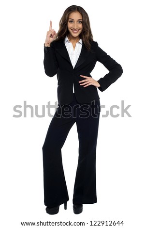 Woman in formals pointing upwards, one hand on waist.