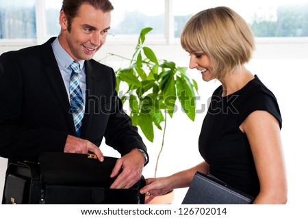 Corporate guy handing over business papers to his secretary before meeting.